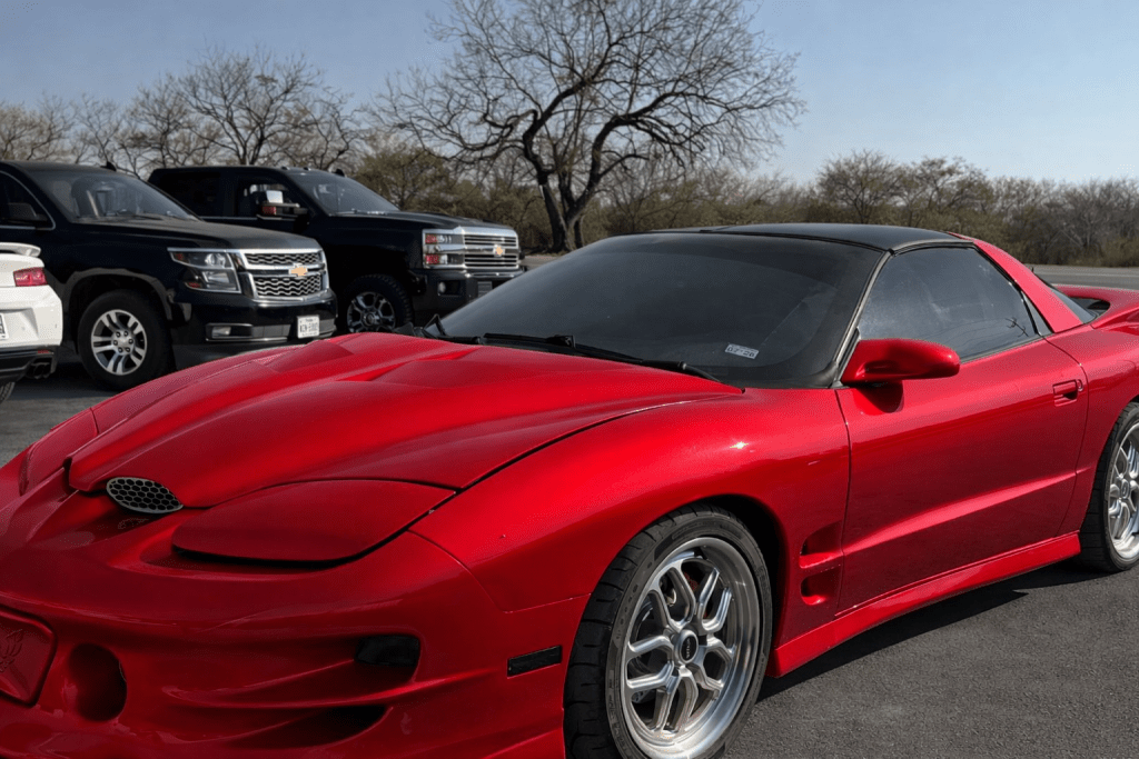 Red Pontiac Trans Am performance car parked outside Nelson Performance automotive tuning shop.